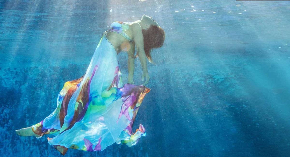 Woman floating in water with light shining down on her symbolizing the feeling of being single and multi-orgasmic!